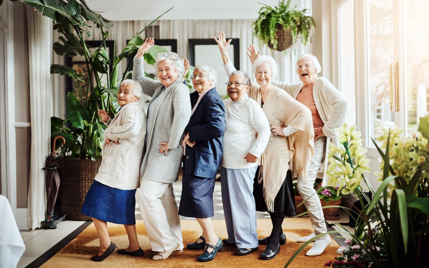 Elderly women dancing in line, waving, laughing, and having fun