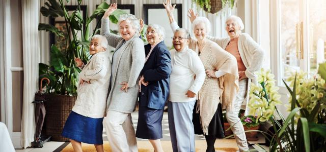 Elderly women dancing in line, waving, laughing, and having fun